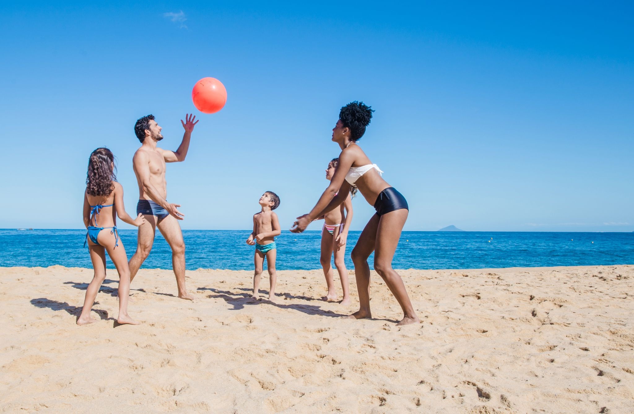 Famille jouant au ballon en bord de mer