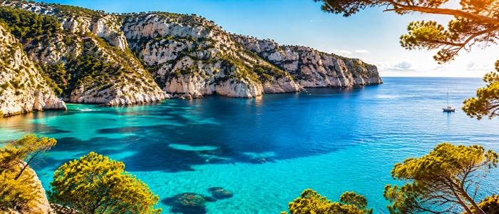 Panorama des Calanques de Cassis avec falaises calcaires, eau turquoise et bateaux, un paysage de France rappelant les îles grecques