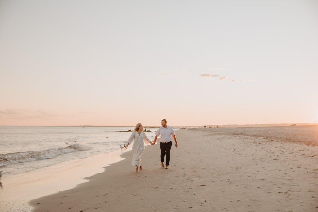 Couple qui marche sur le sable en bord de mer le soir