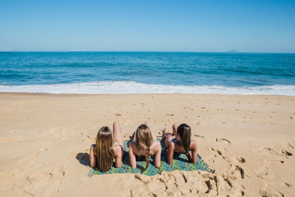 Trois filles allongées sur une serviette de plage devant la mer